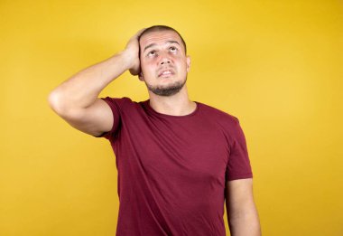 Rus adam sarı üzerine kırmızı tişört giyiyor. Endişeli ve stresli. Alnındaki sorun yüzünden gergin ve bunalımda.