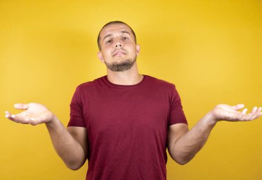 Rus adam, sarı tişört giyiyordu. İzole edilmiş arka plan, bilgisiz ve elleri havada, kafası karışmış bir ifade.