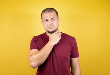 Rus adam sarılı arka planda kırmızı tişört giyiyor. Ağrılı boyuna dokunuyor. Grip, mantar ve enfeksiyon yüzünden boğazı ağrıyor.
