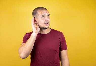 Rus adam sarılı arka planda kırmızı tişört giyiyor. Kulağı kulağında gülümsüyor. Bir dedikoduyu ya da dedikoduyu dinliyor. Sağırlık kavramı.