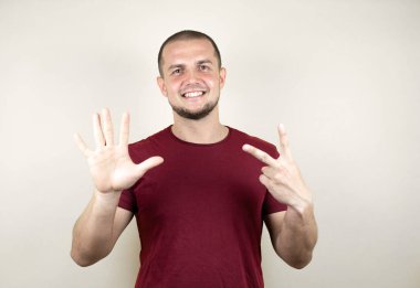 Rus adam, sarı tişörtlü, özgüvenle gülümseyen ve mutlu bir şekilde yedi numaralı parmaklarını göstererek, sarı izole edilmiş arka plan üzerinde temel kırmızı tişört giyiyor..