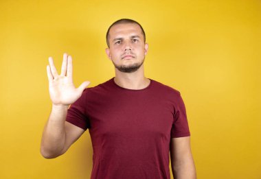 Rus adam sarı izole arkaplan üzerine kırmızı tişört giyip Star Trek ucube sembolü yapıyor.
