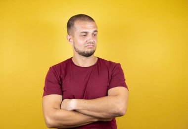 Rus adam sarı tişört giyiyordu. İzole edilmiş arka plan şüpheci ve gergin. Yüzünde çapraz kollu tasvip etmeyen bir ifade vardı.