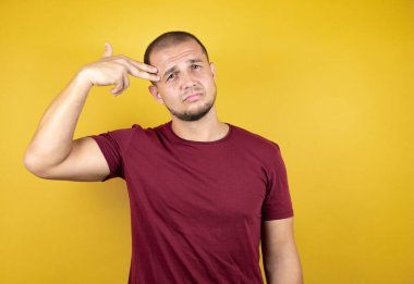 Rus adam, sarının üzerine kırmızı tişört giymişti. İzole edilmiş arka plan üzerinde. Silah gibi el ve parmakları göstererek kendini vurarak ve öldürerek intihar etti..