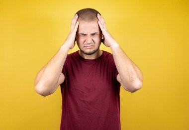 Rus adam sarının üzerine kırmızı t-shirt giymiş. Sararmış arka plan. Baş ağrısı, çaresiz ve stresli.