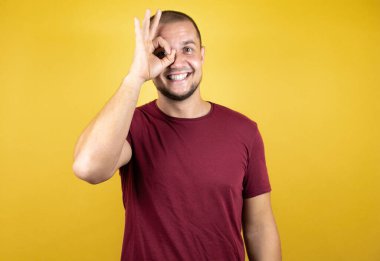 Rus adam sarı arkaplanda kırmızı tişört giyiyor. Şaşırmış yüz ve gözlerle parmaklarından bakıyor.