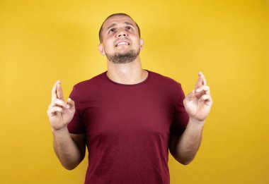 Rus adam sarı arkaplan üzerine kırmızı tişört giyiyor. Umut dolu bir gülümsemeyle işaret ediyor.