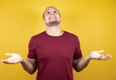 Rus adam, sarı tişört giyiyordu. İzole edilmiş arka plan, bilgisiz ve elleri havada, kafası karışmış bir ifade.