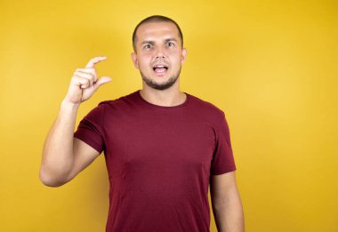 Rus adam sarı arkaplan üzerine kırmızı tişört giyiyor. El işaretleri yapıyor. Parmak işaretleri yapıyor..