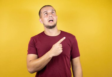 Rus adam, sarı tişört giyiyordu. İzole edilmiş arka plan, gülümsüyordu ve başparmağıyla yan tarafı gösteriyordu..