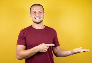 Rus adam, sarı tişört giymişti. İzole edilmiş arka plan hayret içindeydi. Kameraya baktı ve elinde bir şey gösterdi..