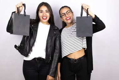 Siyah bir alışveriş çantası tutan iki güzel kadın gülümsüyor. Kara Cuma