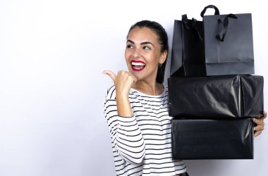 Siyah alışveriş çantaları ve kutular taşıyan genç ve güzel bir kadın. Çok mutlu ve heyecanlı bir şekilde geri işaret ediyor. Kara Cuma