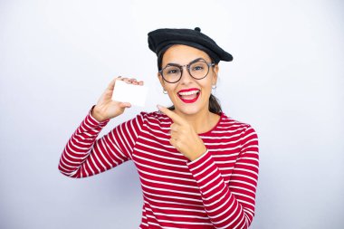 Fransız beresi takmış, beyaz arka planda gözlüklü güzel esmer kadın gülümsüyor ve elinde beyaz kart tutuyordu.