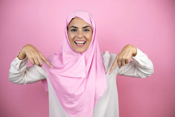 若いです美しいですArab女性身に着けていますイスラムヒジャーブ上の隔離されたピンクの背景を身に着けています自信を持って顔に笑顔 指で自分自身を指して誇りと幸せ — ストック写真