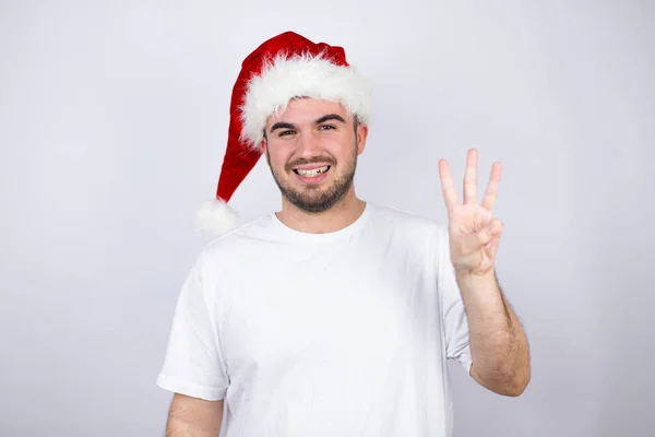Mladý Pohledný Muž Klobouku Santa Nad Bílým Pozadím Ukazuje Ukazuje — Stock fotografie
