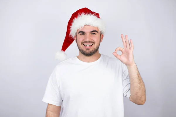 Mladý Pohledný Muž Klobouku Santa Nad Bílým Pozadím Dělá Pořádku — Stock fotografie