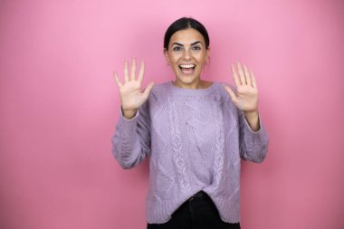 Mutlu ve kendinden emin bir şekilde gülümserken on numarayı göstererek.