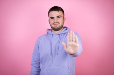 Soyutlanmış pembe arka plan üzerine gündelik eşofman giyen genç yakışıklı adam ciddi ciddi şarkı söylemeyi kesiyor..