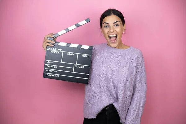 Beautiful Woman Wearing Casual Violet Sweater Pink Background Holding Clapperboard — Stock Photo, Image