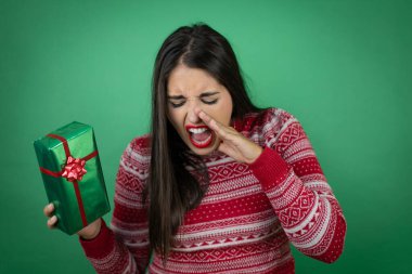 Genç, güzel bir kız, beyaz arka planda hediyesini tutuyor. Elleri ağızda bağırıyor ve bağırıyor.