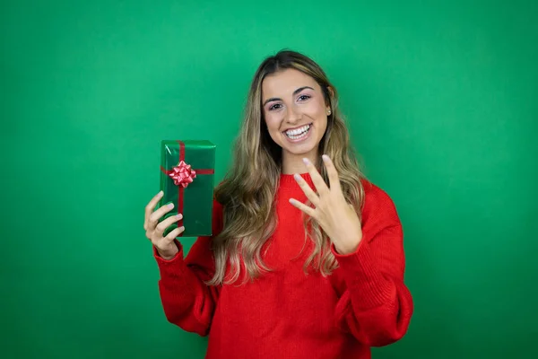 Menina Bonita Jovem Segurando Presente Sobre Fundo Verde Isolado Mostrando — Fotografia de Stock