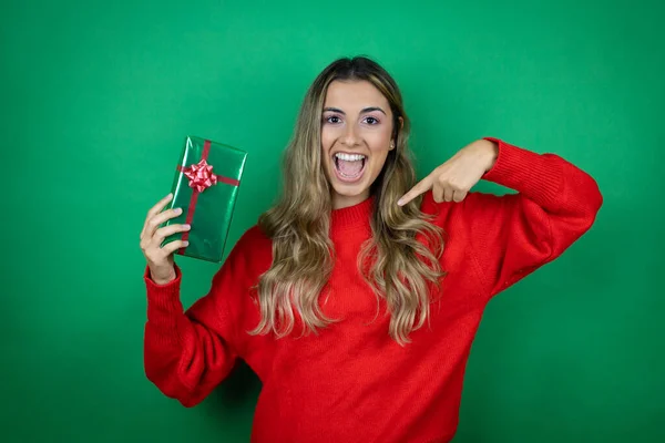 Menina Bonita Jovem Segurando Presente Sobre Fundo Verde Isolado Olhando — Fotografia de Stock