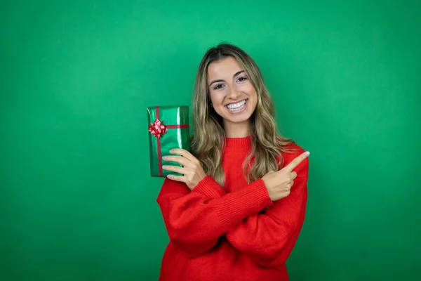 Genç Güzel Bir Kız Yeşil Arka Planda Hediyesini Tutuyor Gülümsüyor — Stok fotoğraf