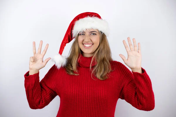 금발의 여자가 드레스를 크리스마스 모자를 배경에 손가락으로 손가락을 자신감 미소를 — 스톡 사진