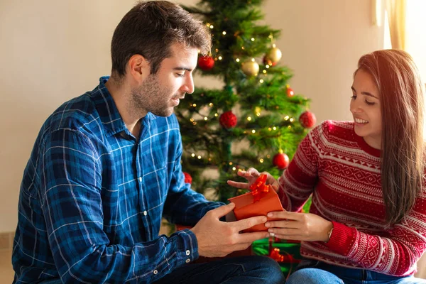 Jeune Couple Souriant Donnant Cadeau Avec Arbre Noël Arrière Plan — Photo