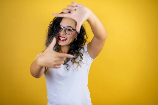 Stock image Young beautiful woman wearing casual white t-shirt over isolated yellow background smiling making frame with hands and fingers with happy face