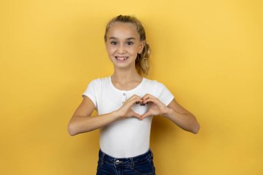 Genç, güzel bir kız çocuğu, izole edilmiş sarı arka planda duruyor. Güzel bir kız çocuğu, izole edilmiş pembe arka planda duruyor. Aşkla gülümsüyor.