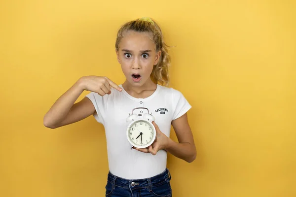 Young Beautiful Child Girl Standing Isolated Yellow Background Holding Clock — Stock Photo, Image