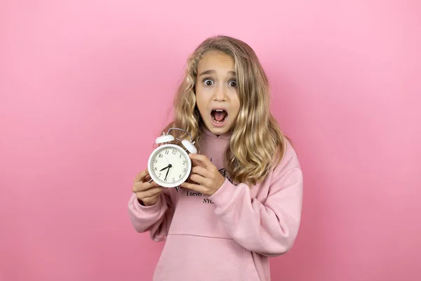 Молодая Красивая Девочка Стоит Изолированном Розовом Фоне Держа Часы Испуганным — стоковое фото