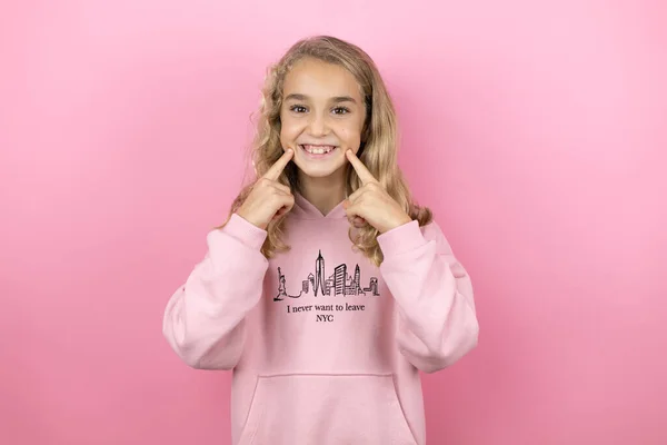 年轻美丽的小女孩站在孤立的粉色背景上 带着自信的微笑 用手指和嘴指点着 — 图库照片