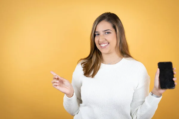 Ung Kaukasiska Kvinna Över Isolerad Gul Bakgrund Leende Visar Telefonen — Stockfoto