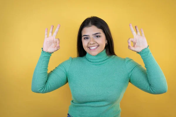 年轻的高加索女人站在孤立的黄色背景上 用手指和微笑做手势 这是一个极好的象征 — 图库照片