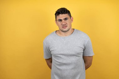 Sarı arka plan üzerinde sıradan bir tişört giyen yakışıklı genç bir adam şaşkınlık ve şaşkınlık dolu bir ifade, korku ve heyecan dolu bir yüz ifadesiyle dehşete düşmüş ve şok olmuştu..