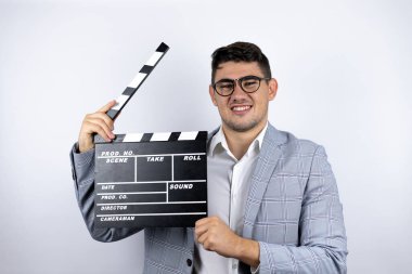 İş adamı beyaz arka plan üzerine sıradan bir tişört giymiş elinde klaket tutarken çok mutlu oluyor.