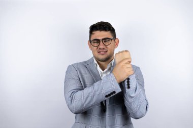 İş adamı beyaz arka planda sıradan bir gömlek giyiyor. Ellerinde ve parmaklarında ağrı, eklem iltihabı var.