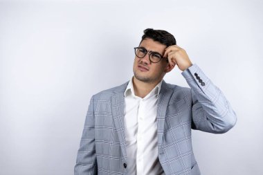 Beyaz arka plan üzerine sıradan bir tişört giyen genç bir iş adamı soru sormayı merak ediyor. Şüpheyle karışık, kafa kafaya düşünerek.