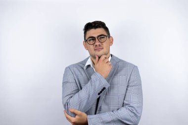 İş adamı beyaz arka plan üzerine sıradan bir tişört giymiş düşünceli bir genç.