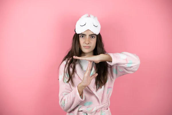 Pretty girl wearing pajamas and sleep mask over pink background doing the call me gesture with her hands