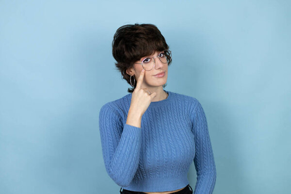 Young caucasian woman over isolated blue background Pointing to the eye watching you gesture, suspicious expression