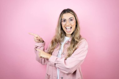 Pembe arka planda duran uzun saçlı güzel sarışın kadın iki eliyle fotokopi alanını işaret ediyor.