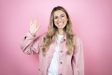 Pembe arka planda duran uzun saçlı güzel sarışın kadın Star Trek ucube sembolü yapıyor.