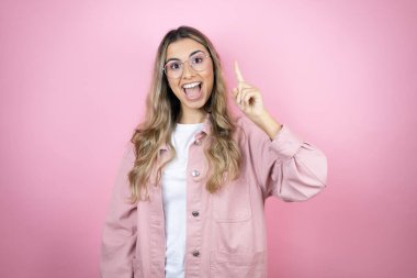 Pembe arka planda duran uzun saçlı güzel sarışın kadın şaşırdı ve parmağıyla kafasında bir fikri olduğunu sandı..