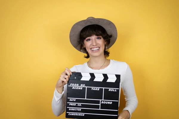 Young Caucasian Woman Wearing Hat Isolated Yellow Background Holding Clapperboard — Stock fotografie