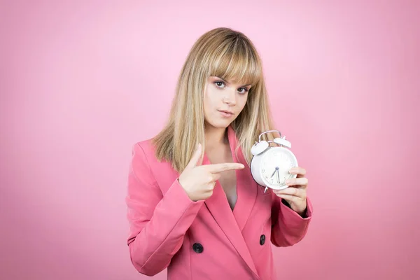 Молодая Белая Женщина Изолированном Розовом Фоне Серьезно Указывая Часы Потому — стоковое фото