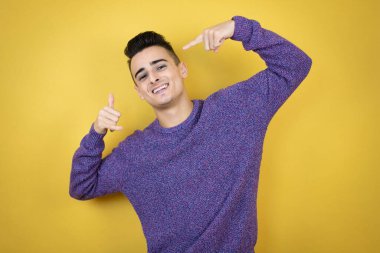 İzole edilmiş sarı arka planda genç beyaz adam bana elleriyle jest yapıyor.